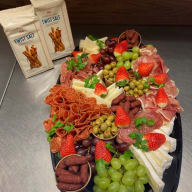 Bicka med små ölkorvar, vindruvor, brieost, gröna oliver med pimento, Olika sorters lufttorkad salami, lufttorkad skinka, bitar med hårdost och jordgubbar. Två paket med twisted salt kex