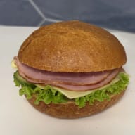 Rund smörgås med skivad skinka, ost och salladsblad.