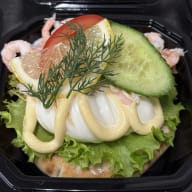 Öppen smörgås med räkor och skivat kokt ägg garnerad med dill och gurkskiva.