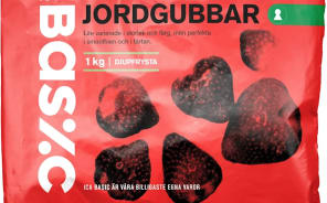 En förpackning med jordgubbar ligger på ett underlag.