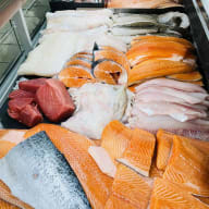 Ett urval av filéer och fiskstycken upplagda på is i en fiskdisk.