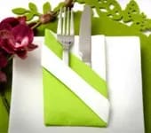 En tallrik med bestick och en servett bredvid en blomma.