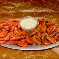 Uppläggningsfat med räkor som omger en skål med dippsås.