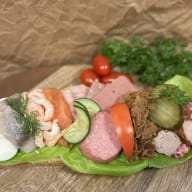 Öppet smörgåsbröd med blandade pålägg som ägg, räkor, lax, kallskuret och inlagda grönsaker.