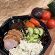 Platstallrik med skivor kryddat kött, potatissallad och bladig sallad.