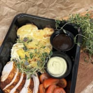 Matlåda med skivad kyckling, potatisgratäng, körsbärstomater och sås.