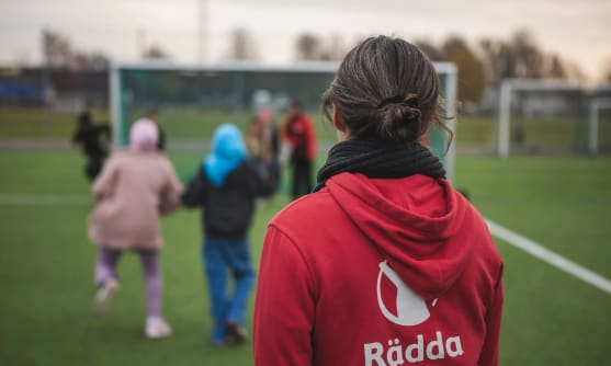 En person står på en fotbollsplan och tittar mot ett mål.