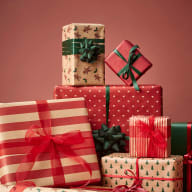 Staplad hög med inslagna presenter dekorerade med band och rosetter.