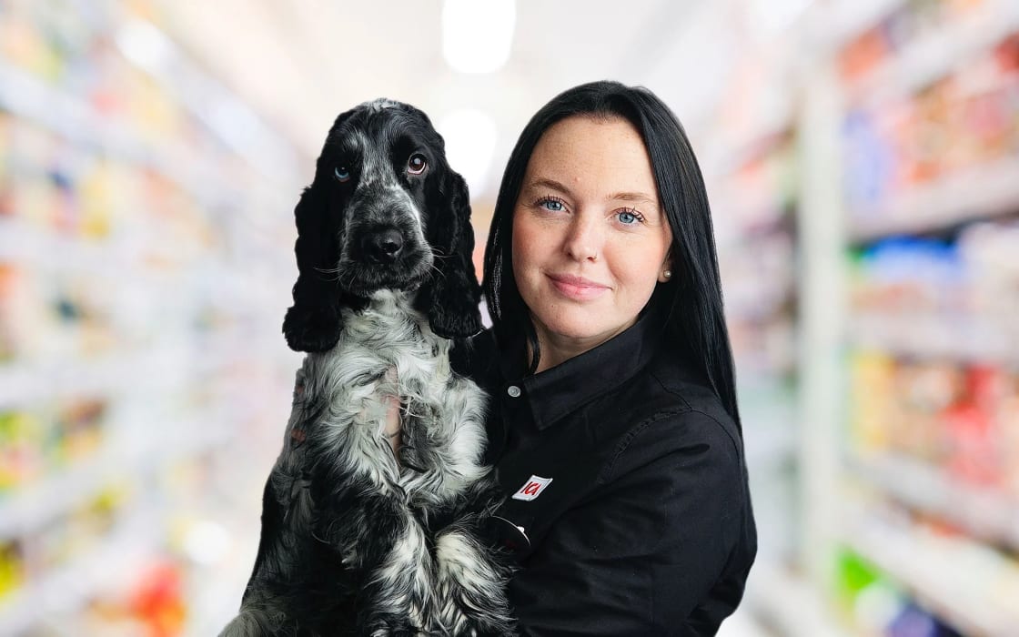 En person håller en cocker spaniel i famnen i en mataffärsgång.