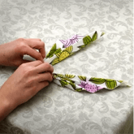 En person viker en tygservett med blommönster på en duk.