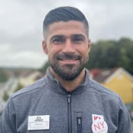 En ICA-anställd i arbetsjacka med namnskylt.