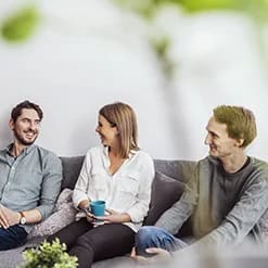Tre personer pratar i en soffa.