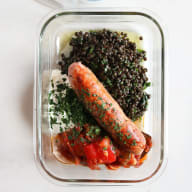 Matlåda med korv, linser och ratatouille på en ljus bakgrund