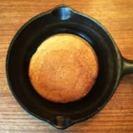 En pannkaka ligger i en gjutjärnspanna på ett träbord.