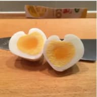 Ett hårdkokt ägg skuret i halvor ligger på ett bord bredvid en kniv.