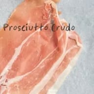 En skiva prosciutto crudo med synlig marmorering och text.
