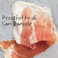 En bit prosciutto ligger på en yta med text som beskriver typen av skinka.