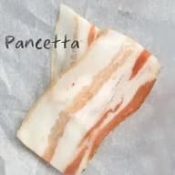 En bit pancetta ligger på en grå yta med texten 