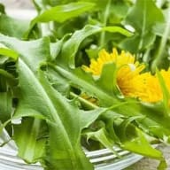 En sallad med blad och en blomma på en tallrik.