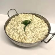 Krämig potatissallad i en serveringsskål, toppad med dill.