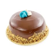 Chokladtårta med nötter runt kanten och blå samt vit marsipanblomma på toppen.