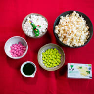 En bild visar skålar med popcorn, marshmallows och godis på ett bord.