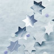 En girlang med silvriga stjärnor på rad med en grå bordsduk i bakgrunden.