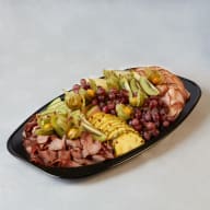 Uppläggningsfat med tunt skivade charkuterier och skuren frukt.