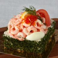 Smörgåstårta toppad med räkor, ägg, rom och dill.