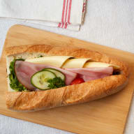 Baguette fylld med skivad skinka, ost och färska grönsaker.