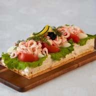 Smörgåstårta toppad med räkor, ägghalvor, tomatbitar och dill.
