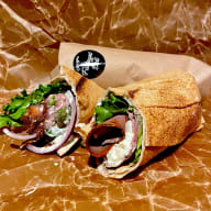 Halverad wrap fylld med rostbiff, sallad, lök och krämig fyllning. förpackningen har butikens sigill påklistrat.