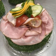 Rund smörgåstårta med skinka, tomat, gurka, apelsin och persilja.