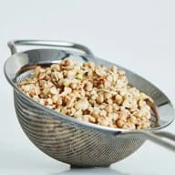 En metallsil innehåller krossade nötter eller frön.