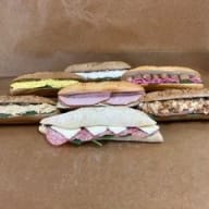 Flera smörgåsar med olika fyllningar ligger på ett papper.