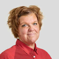 En person med kort hår ler mot kameran och bär en skjorta med krage.