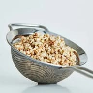 En metallsil innehåller krossade nötter eller frön.