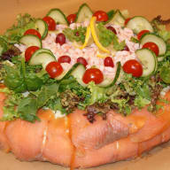 En sallad med grönsaker och lax serveras på ett fat.