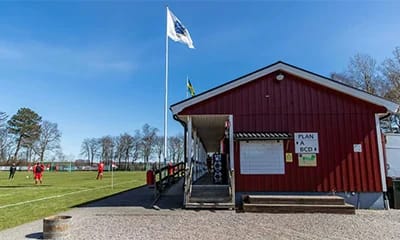 Ett rött hus med en flaggstång i bakgrunden.