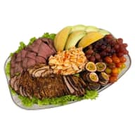 Serveringsfat med assorterade skivade köttstycken och blandad frukt.