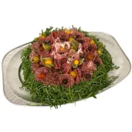 Uppläggningsfat med ett arrangemang av skivad charkuterier, körsbärstomater, oliver och bladgrönt.