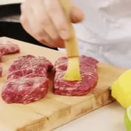 Penslar kött med olja inför grillning.