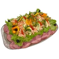 En smörgåstårta toppad med räkor och olika garnityrer, omgiven av skivor skinka.