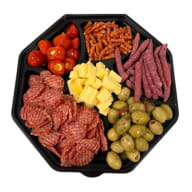 Ett upplagt charkfat med tärnad ost, skivat chark, oliver, fyllda paprikor och snacks.