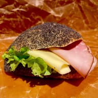 Fröfralla fylld med skinka, ost och sallad mot en pappersbakgrund