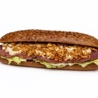 Lång smörgås fylld med sallad, skivat kött, krämig röra och knaprigt friterad lök.
