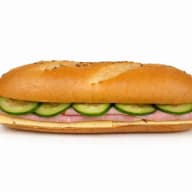 En baguette fylld med skivor av skinka, ost och gurka.