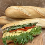 Baguettesmörgås fylld med krämig äggsallad, salladsblad och grönsaker.
