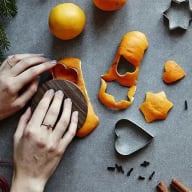 Någon använder stjärnformade och hjärtformade pepparkaksformar för att stansa ut bitar av apelsinskal.