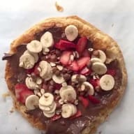 Steg 4 Nutellapizza: Toppa pizzan med dina favoriter. Här har vi använt skivade bananer och jordgubbar, samt hackade hasselnötter.